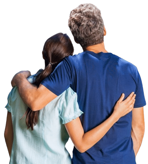Couple embraces, looking at their home. Considering house painting options, they stand with arms around each other, gazing upwards at the exterior of their house.